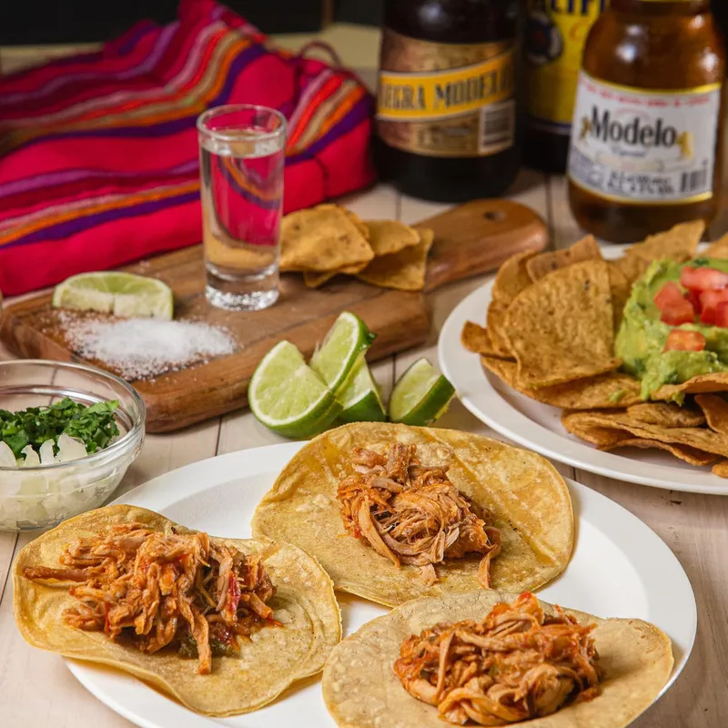 Table with tacos, guacamole and Mexican beers